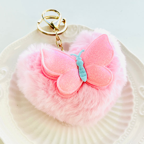 Llavero con pompón en forma de corazón y diseño de mariposa rosa